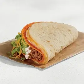 A Doritos® Cheesy Gordita Crunch with Nacho Cheese, featuring a soft flatbread wrapped around a crunchy taco shell, filled with seasoned beef, crisp lettuce, cheddar cheese, and cool ranch sauce.